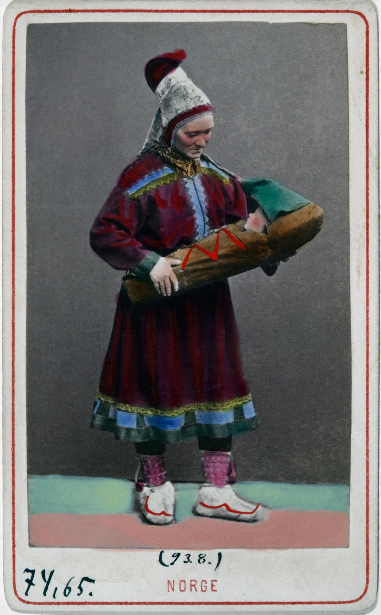 Woman in traditional Norwegian Sámi dress with red tunic, colorful bands, and distinctive hat holding wooden object.